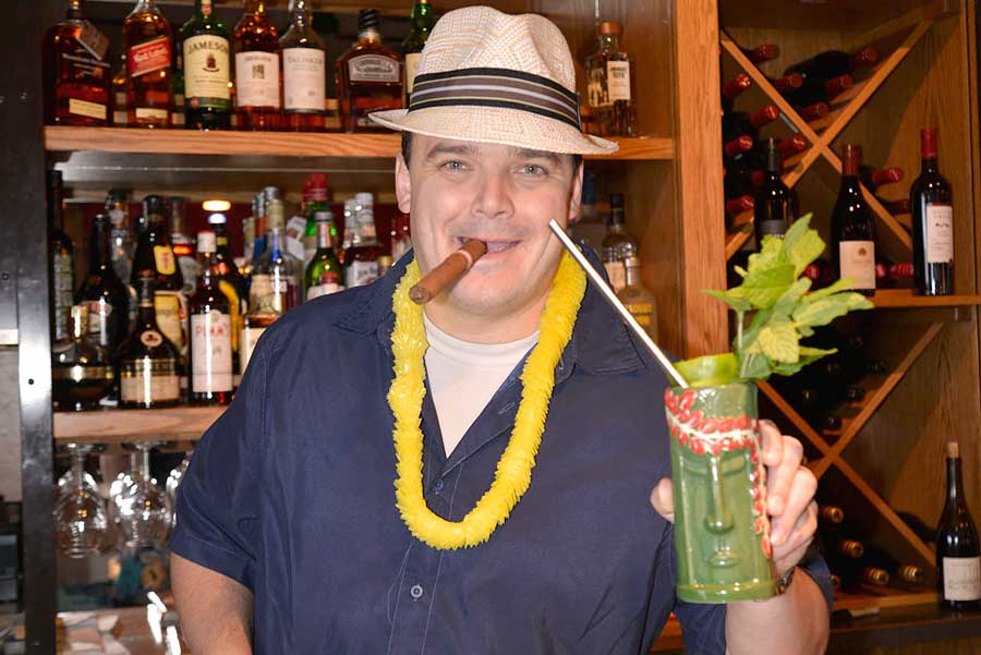 a man with a hat holding a green drink
